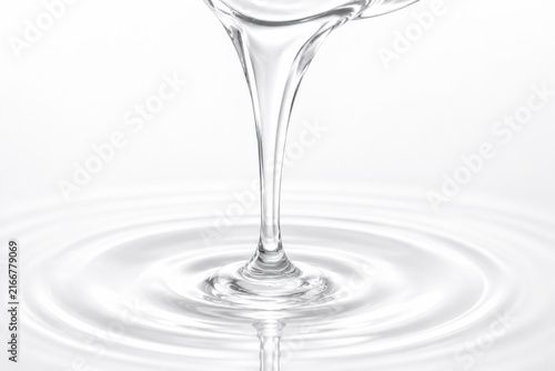 Clear Liquid Stream Creating Concentric Ripples on White Background