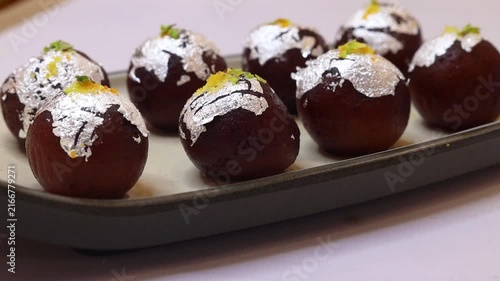 Kala jam or gulab jamun garnished and served on a white fancy plate
