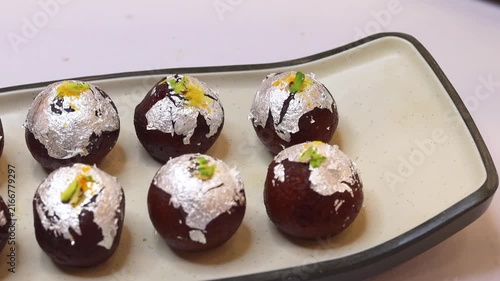 Kala jam or gulab jamun garnished and served on a white fancy plate
