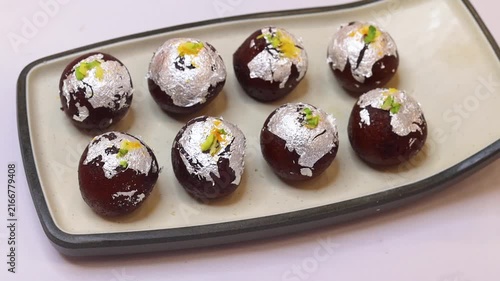 Kala jam or gulab jamun garnished and served on a white fancy plate