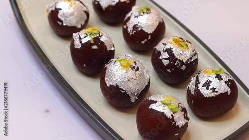Kala jam or gulab jamun garnished and served on a white fancy plate