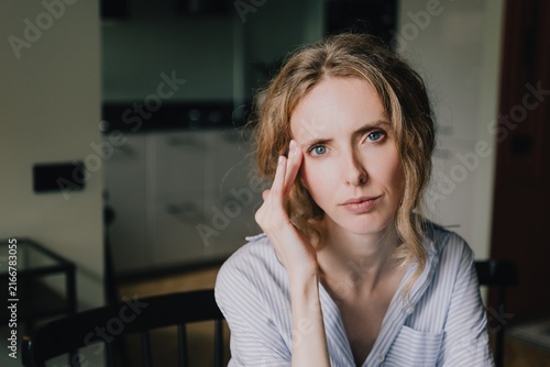 Thoughtful woman touching her temple while experiencing mental fatigue and cognitive overload at home
