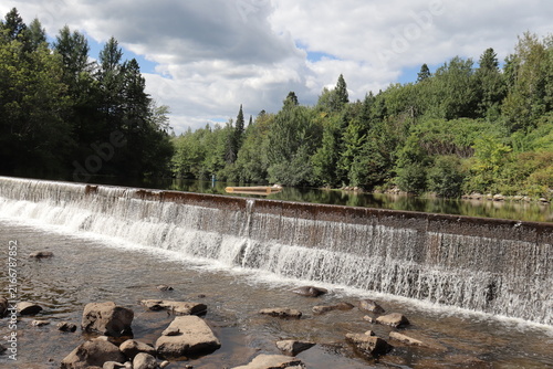Dam in the mountain. Panorama of a picturesque landscape in summer and St-Charles in Quebec city. Beautiful river with trees reflections and waterfalls. Protection of the water and environment.