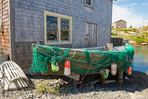 Weathered boat with fishing net and buoy's tied on in a fishing village at Peggy's Cove in summer