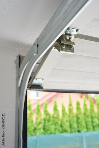 Garage door track, hinge and metal hardware with sectional door partly open