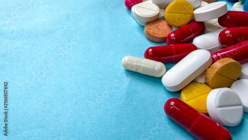 Foto Pile of colorful medical pills capsules and tablets on light blue background with copy space