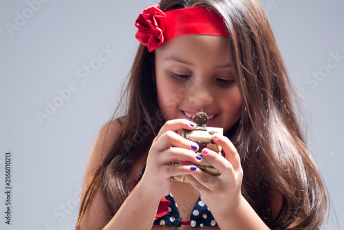 Happy little girl with red headband holding and looking at a small wooden treasure box with curiosity