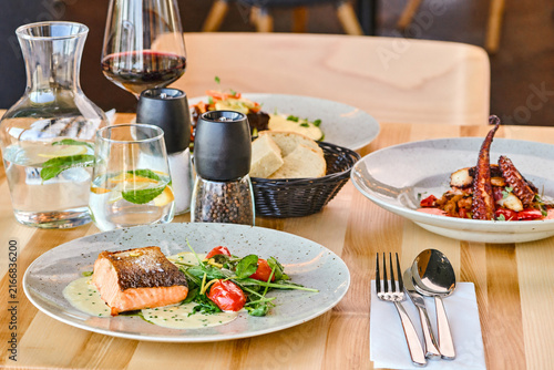 Gourmet seafood dishes served on wooden table in modern restaurant setting