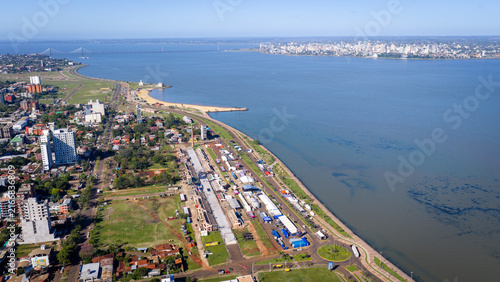 Bild auf Leinwand Wide aerial shot of Encarnacion's waterfront with a distant bridge connecting to Posadas skyline