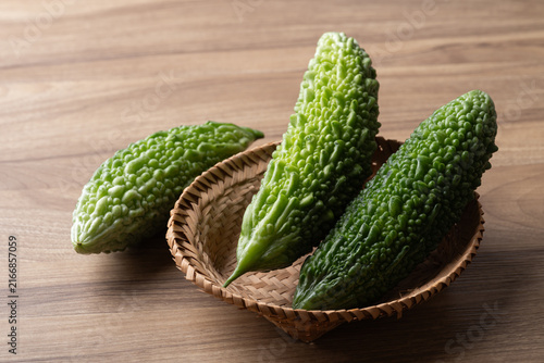 Canvastavla Fresh bitter gourd or bitter melon in a basket on a wooden background, Asian veg