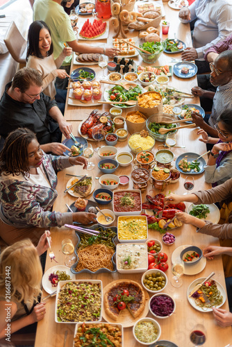 Diverse men and women sharing a large communal meal around a table