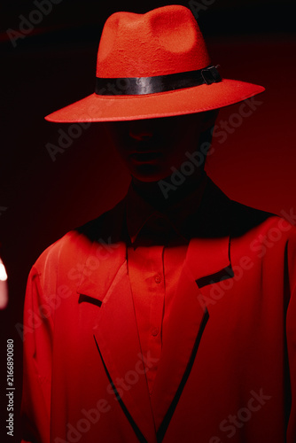 Foto Portrait of a mannequin wearing a striking red suit and wide-brimmed red hat with a dark band, lit by dramatic moody lighting