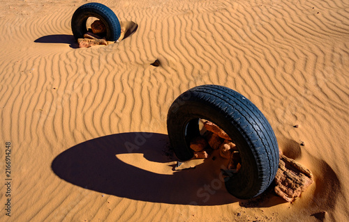 Fotografía Close up view of a discarded old car tire half buried in desert sand