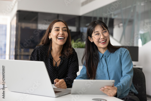Cuadro en lienzo Two happy diverse women teammates, corporate employees take break seated at desk