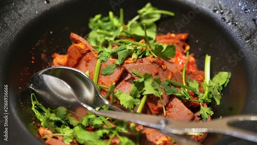 black bowl full of with vegetables and meat, dish with basil leaves on top