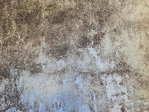 Weathered plaster shows signs of age and neglect. Stains and peeling texture tell a story of time passage. Soft gray and brown tones create a moody, textured backdrop. Suitable for design, film