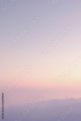Soft pastel sky transitioning from gentle purple above to pink and peach near the horizon, with faint misty clouds below, evoking tranquil beauty of sunrise or sunset.