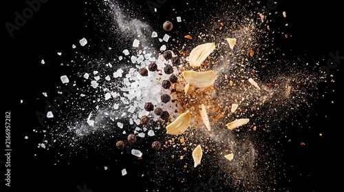 Salt crystals pepper corns and garlic slices colliding in mid air against black background with dynamic explosion seasoning ingredients peppercorns preparation scattering collision particles with food