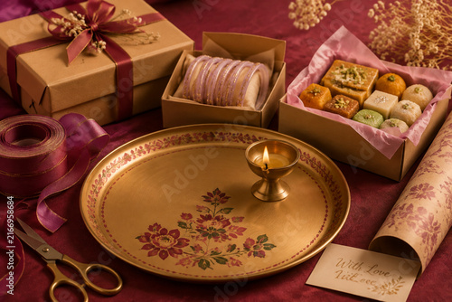 Decorated thali, brass diya, bangles, and wrapped sweets for Diwali gift giving and festive celebration