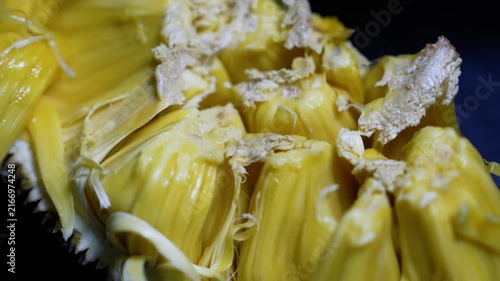Close-up of ripe jackfruit pieces with yellow flesh and fibrous texture on a dark background