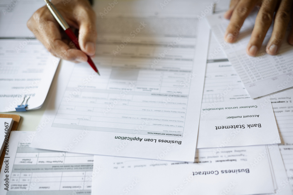 Obraz premium close up shot, man hand checking loan document and business contract to apply for a business startup loan, doing online business, E-commerce business, select focus on document