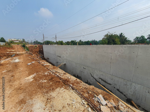 New concrete retaining wall construction site with dirt foreground.