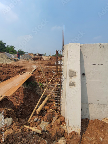Concrete wall construction site with exposed rebar reinforcements.