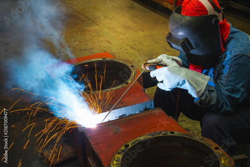Industrial welder welding fabricated construction in factory, Welding process by Shielded Metal Arc Welding (SMAW) or Stick Welding.