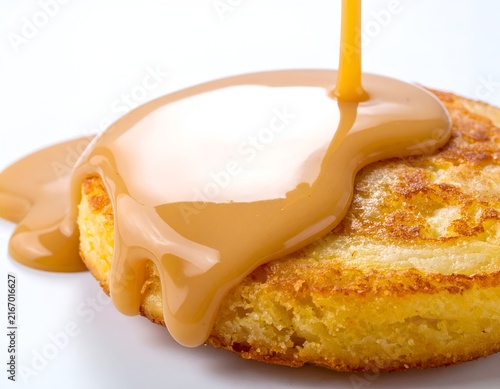 Pouring caramel sauce over a golden round pancake.