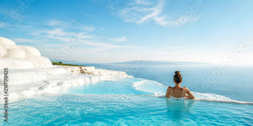 Woman relaxing in a turquoise infinity pool at a luxury spa overlooking the ocean