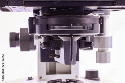 Close-up of a laboratory microscope showing the mechanical stage, adjustment controls, condenser assembly and precision positioning mechanism.