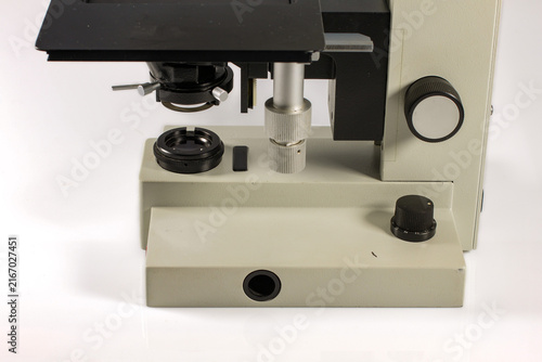 Vintage laboratory microscope featuring a mechanical stage, glass slide holder, adjustable focusing controls and integrated illumination system, photographed against a clean white background.