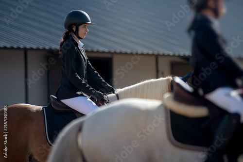 teenage girl in riding attire waits on her horse, anticipating being called to participate in the show jumping competition on the track.
