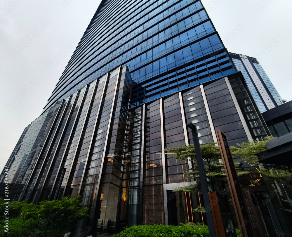 Naklejka premium Ground level plaza with columned entrance, inviting steps and greenery frame office lobby.