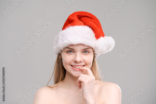 фотографія Playful Woman in a Santa Hat with a Finger on Her Lip