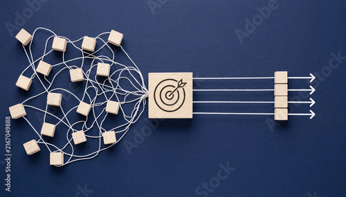 Tangled white strings with scattered wooden blocks converging through a bullseye target and emerging as straight arrows and aligned cubes representing operational streamlining and strategic business.
