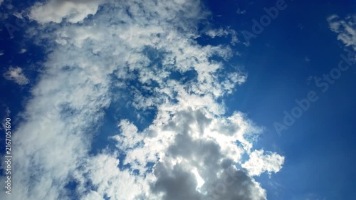 Sunburst Behind White Cumulus Clouds in Blue Sky