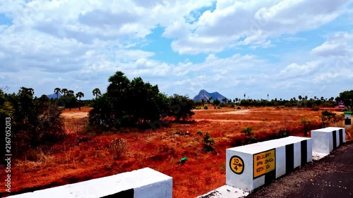 Rural Red Soil Landscape and Distant Hills Under Blue Sky