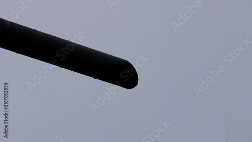 Abstract Geometry: A dark, smooth, cylindrical object extends diagonally across a pale, overcast sky, creating a minimalist and abstract composition.
