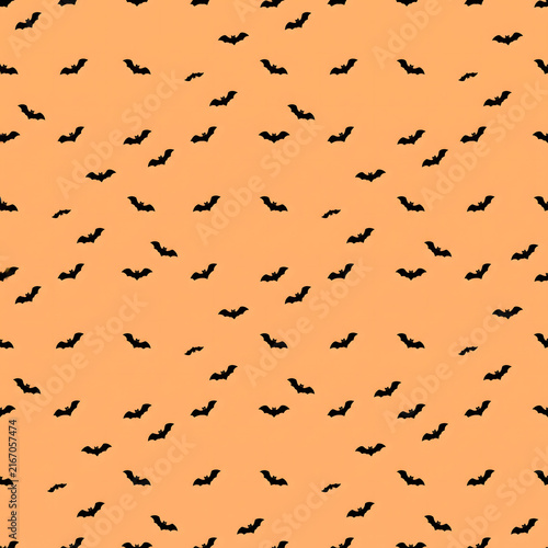 Seamless Halloween Pattern with Flying Black Bats Silhouettes on Bright Orange Background