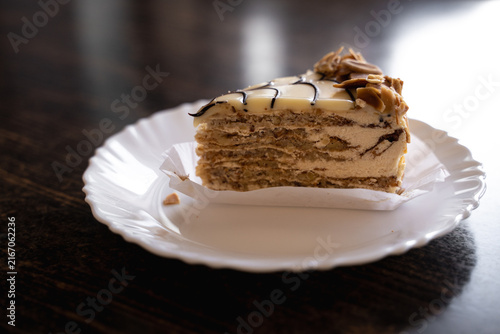 Canvastavla Traditional Esterházy cake served on a white ceramic plate on a wooden cafe table