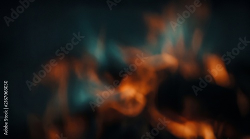 A moody and atmospheric abstract image, featuring a deep black backdrop infused with hints of dark teal and rich orange. Subtle, blurred glowing shapes create a sense of movement and warmth against th