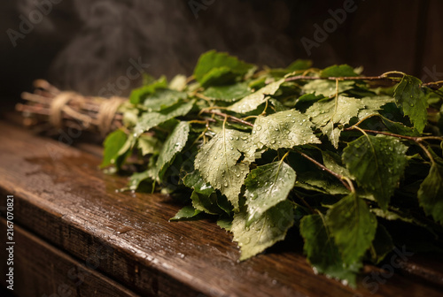 Fresh Birch Sauna Whisk with Water Drops on Wooden Bench