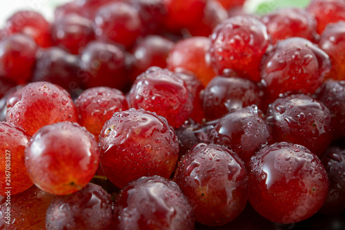 Fresh red grapes glistening with water droplets, vibrant and juicy clusters of fruit