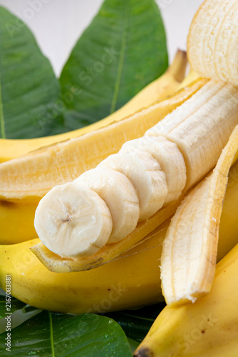 Fresh sliced banana arranged beautifully with green leaves on white background