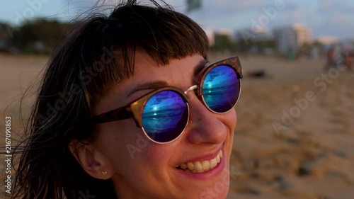 Portrait of a young woman in sunglasses reflecting the sunset. Concept of summer beach vacation. A sense of freedom and summer rest. summer mood. moment of happiness. 

