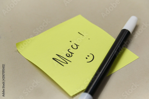 Konstfotografi Handwritten Merci Thank You text in French on yellow sticky note with marker pen