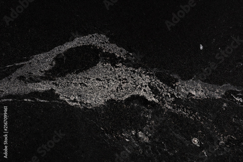 Black granite slab texture with white speckled mineral vein