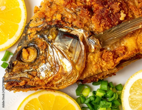 Fried fish closeup with lemon and green onions