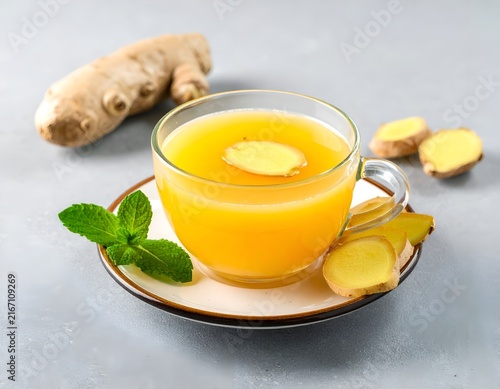 Ginger tea on saucer with fresh ingredients.